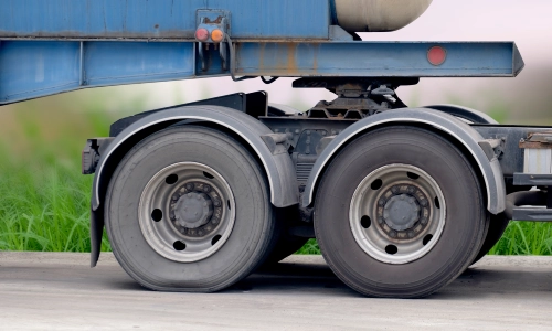 Close up of a freight truck's wheels with one flat tire