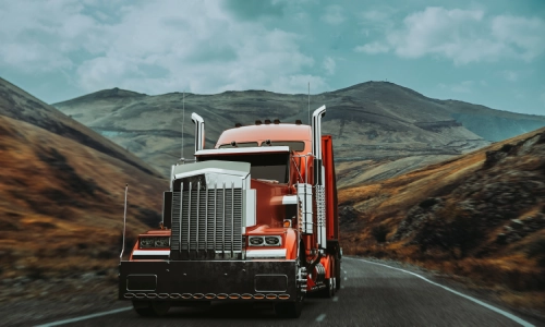 A red freight truck with mountains in the background