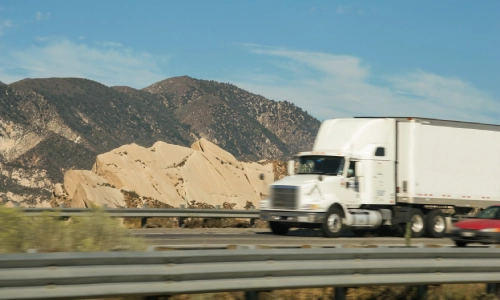 A freight truck in the highway with a hill in the background