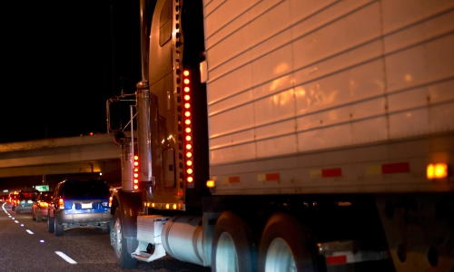 A freight truck in slow traffic at night