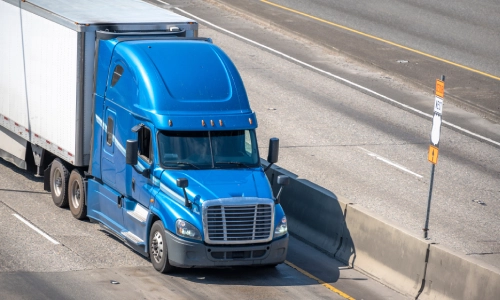 A blue freight truck in the left lane