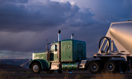 Green freight truck driving on a cloudy day
